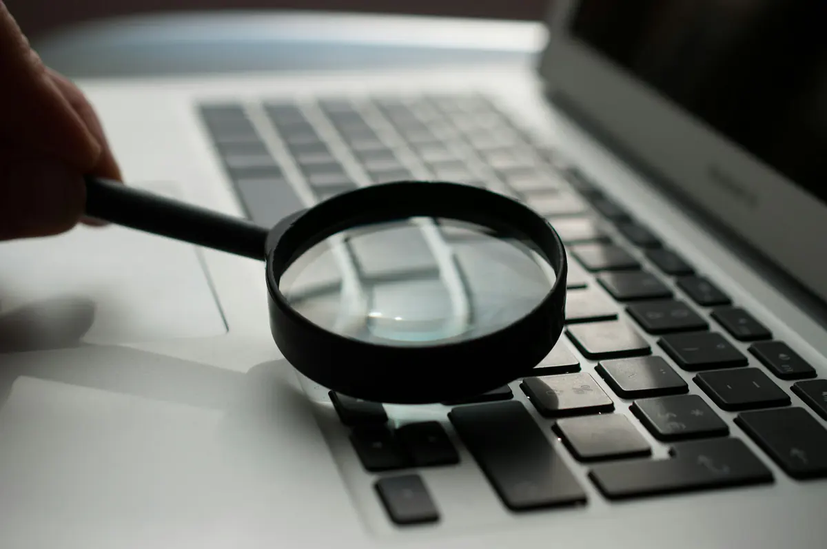 Lupa apoiada sobre o teclado de um notebook.