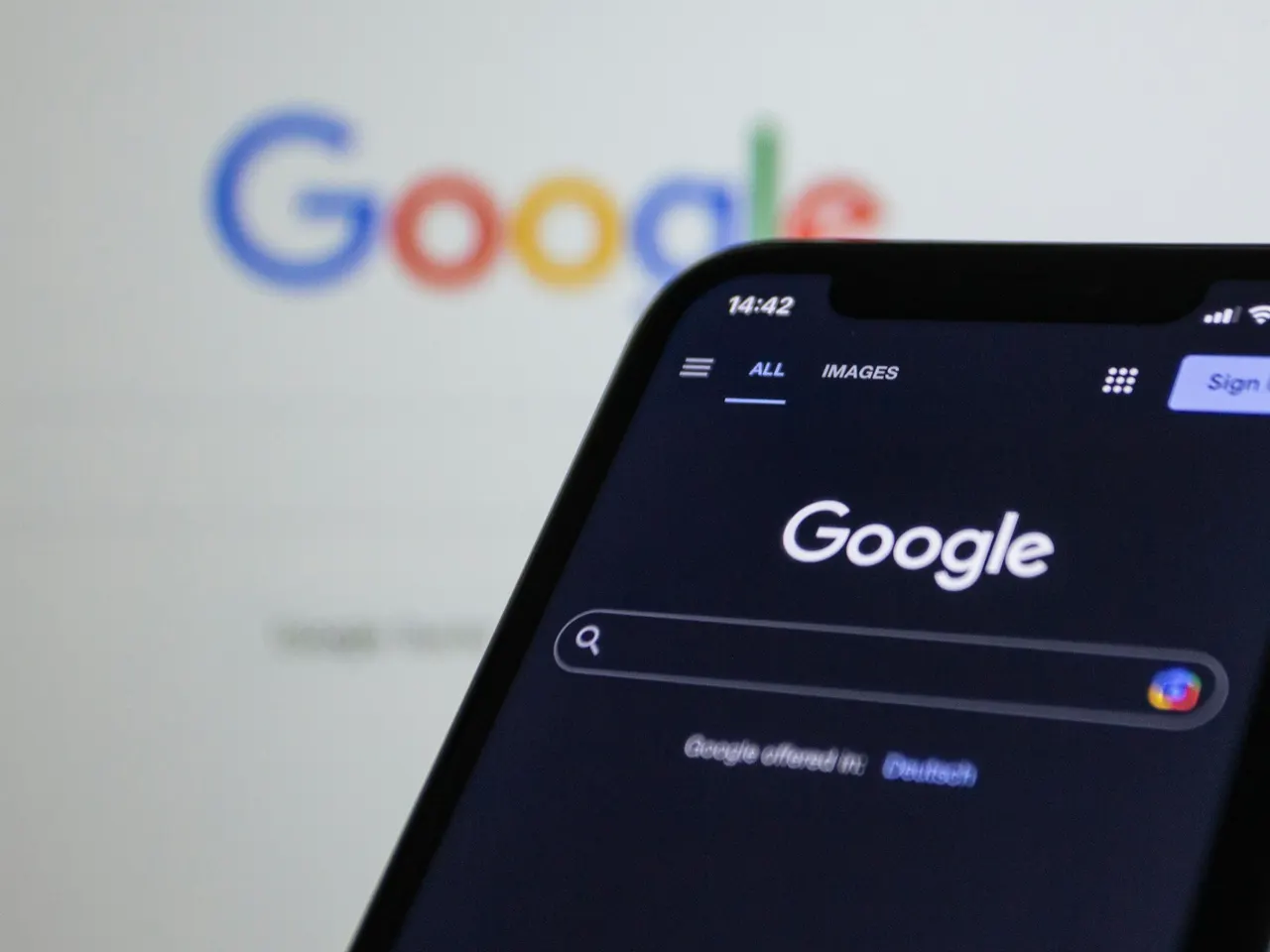 Celular com a busca do Google aberta na tela e o logotipo do Google ao fundo.